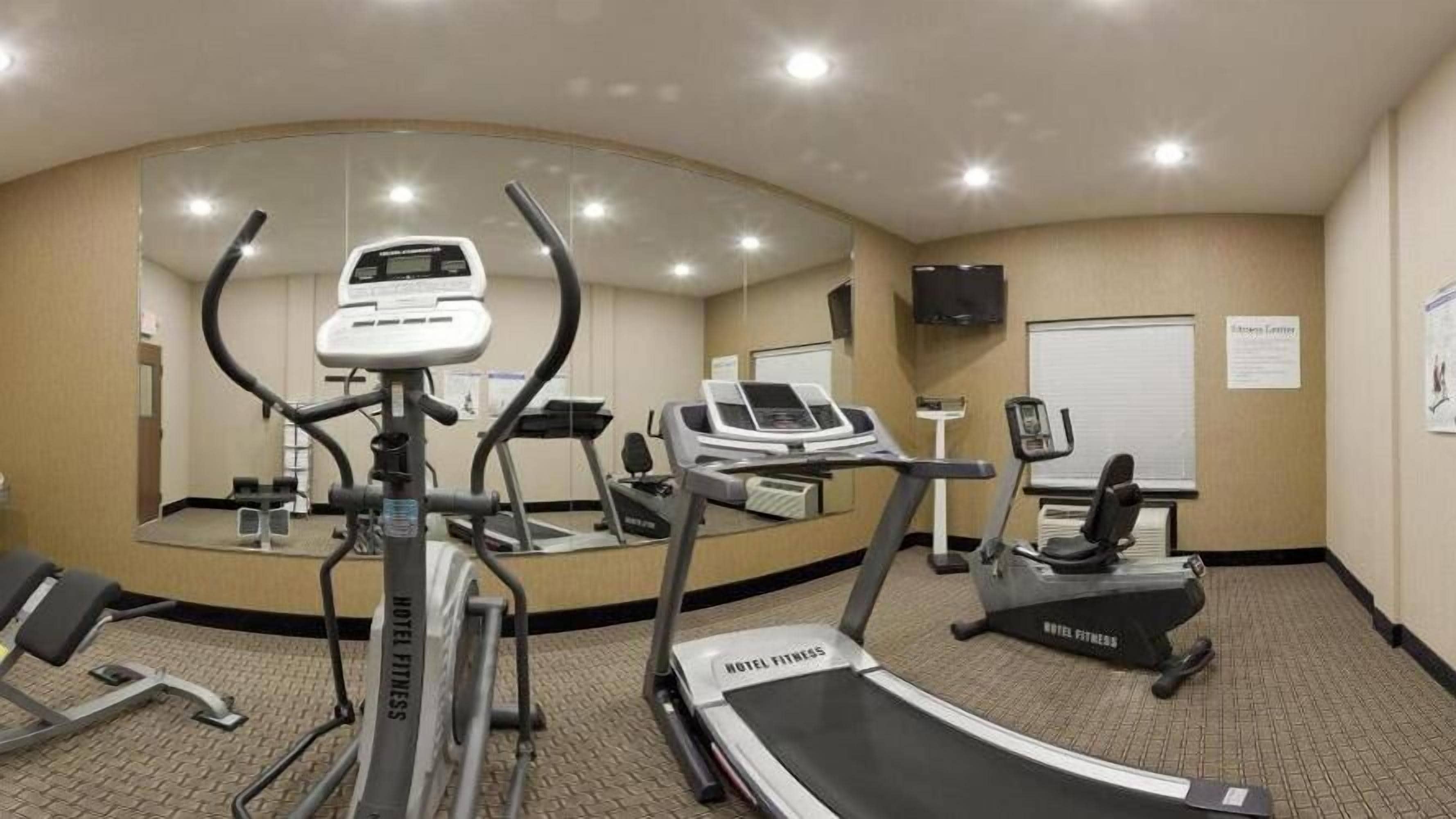 Ein Fitnessraum im Hotel mit Laufbändern, Crosstrainern und einer Spiegelwand.