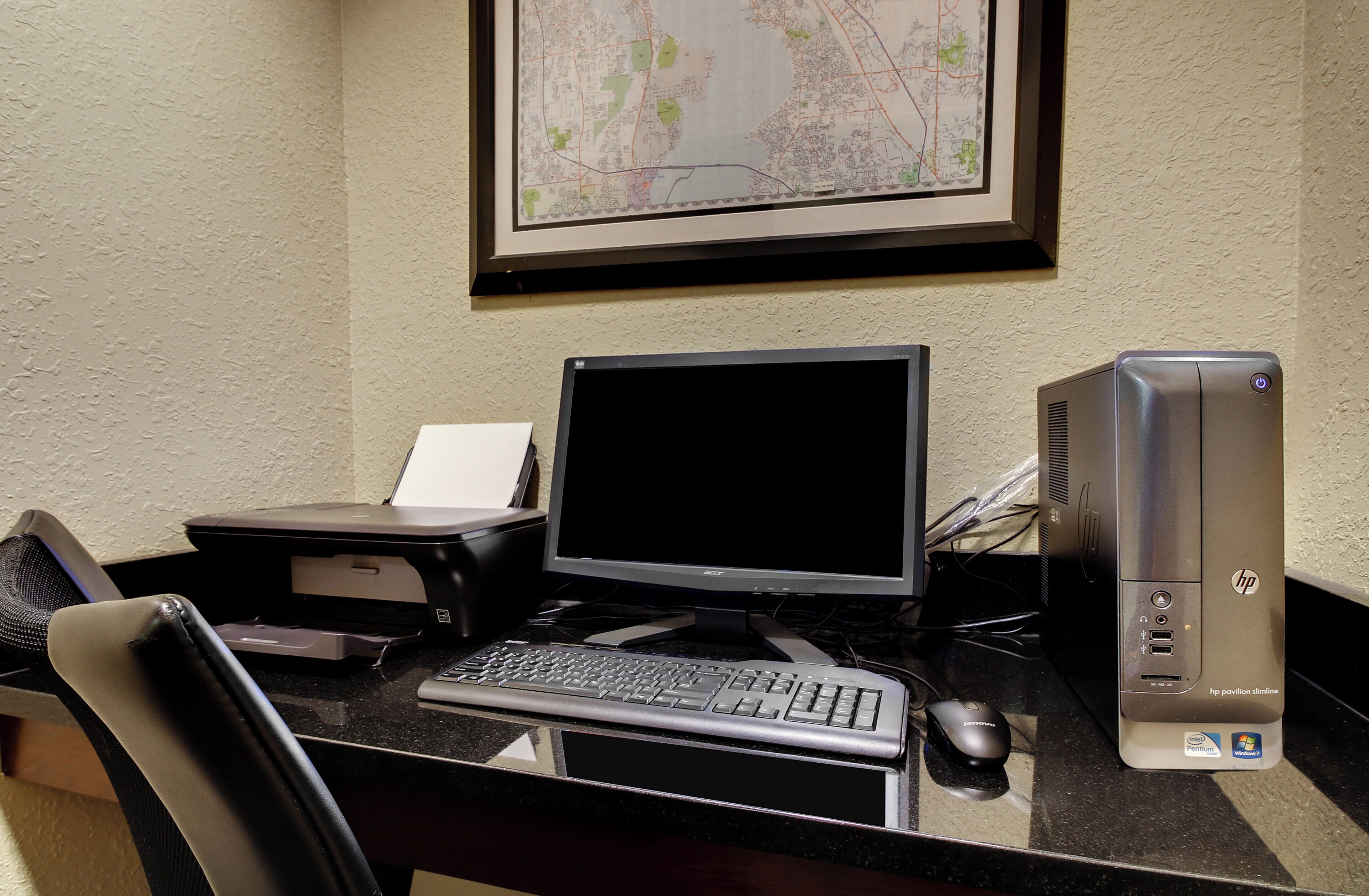 A desktop computer setup with a monitor, keyboard, mouse, and printer on a desk.