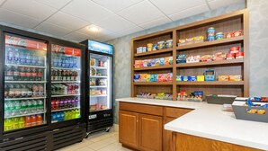 A vending area with Coca-Cola and Sprite coolers, a refrigerated display, and shelves stocked with snacks and drinks.