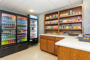 A vending area with Coca-Cola and Sprite coolers, a refrigerated display, and shelves stocked with snacks and drinks.