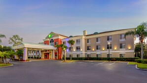 A hotel with a central courtyard, multiple floors, and a prominent green sign. - Holiday Inn Express Hotel & Suites Jacksonville South I-295 by IHG (Jacksonville)