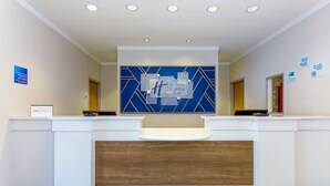 A hotel reception desk with a modern design, featuring a blue and white color scheme, a wooden accent panel, and a digital display above the counter. - Holiday Inn Express Hotel & Suites Jacksonville South I-295 by IHG (Jacksonville)
