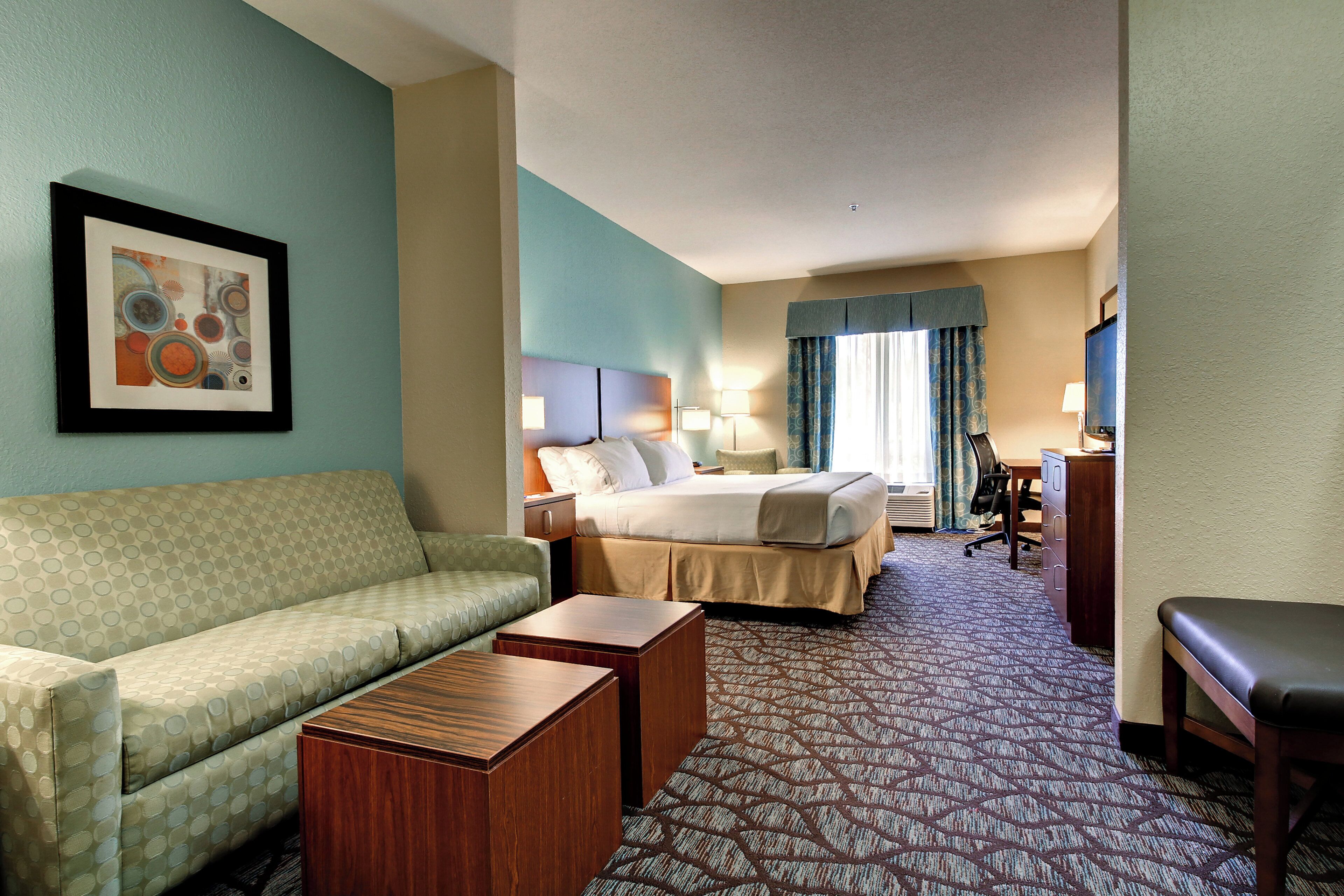 A hotel room with a bed, a sofa, a desk, and a television.