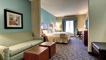 A hotel room with a bed, a sofa, a desk, and a television.