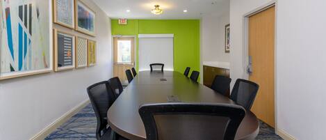 A conference room with a long table, multiple chairs, and framed artwork on the walls.
