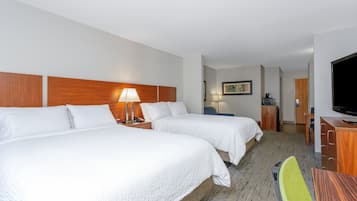 A hotel room with two beds, a desk, a chair, a television, and a bathroom visible in the background.