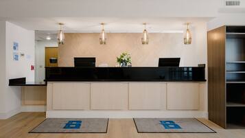 A reception area with a black counter, wooden paneling, and pendant lighting.