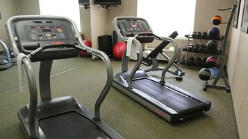 A gym with treadmills, exercise balls, and dumbbells.