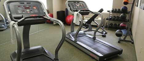Un gimnasio con cintas de correr, pelotas de ejercicio y mancuernas.