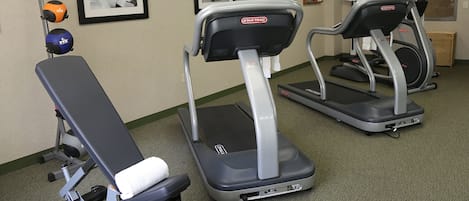 Ein Fitnessraum mit Laufbändern, einer Bank und Trainingsbällen.