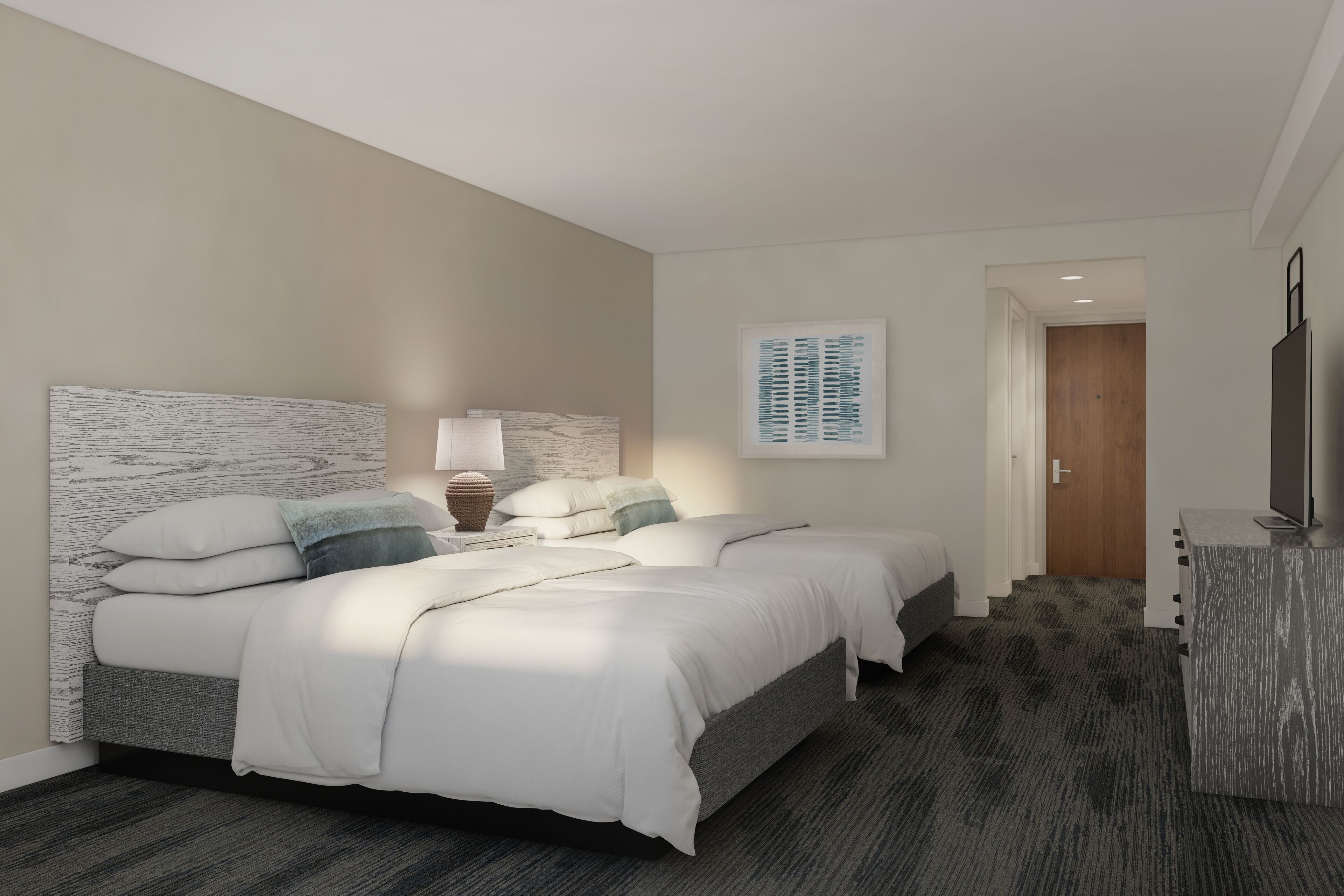 A hotel room with two beds, a desk, and a TV.