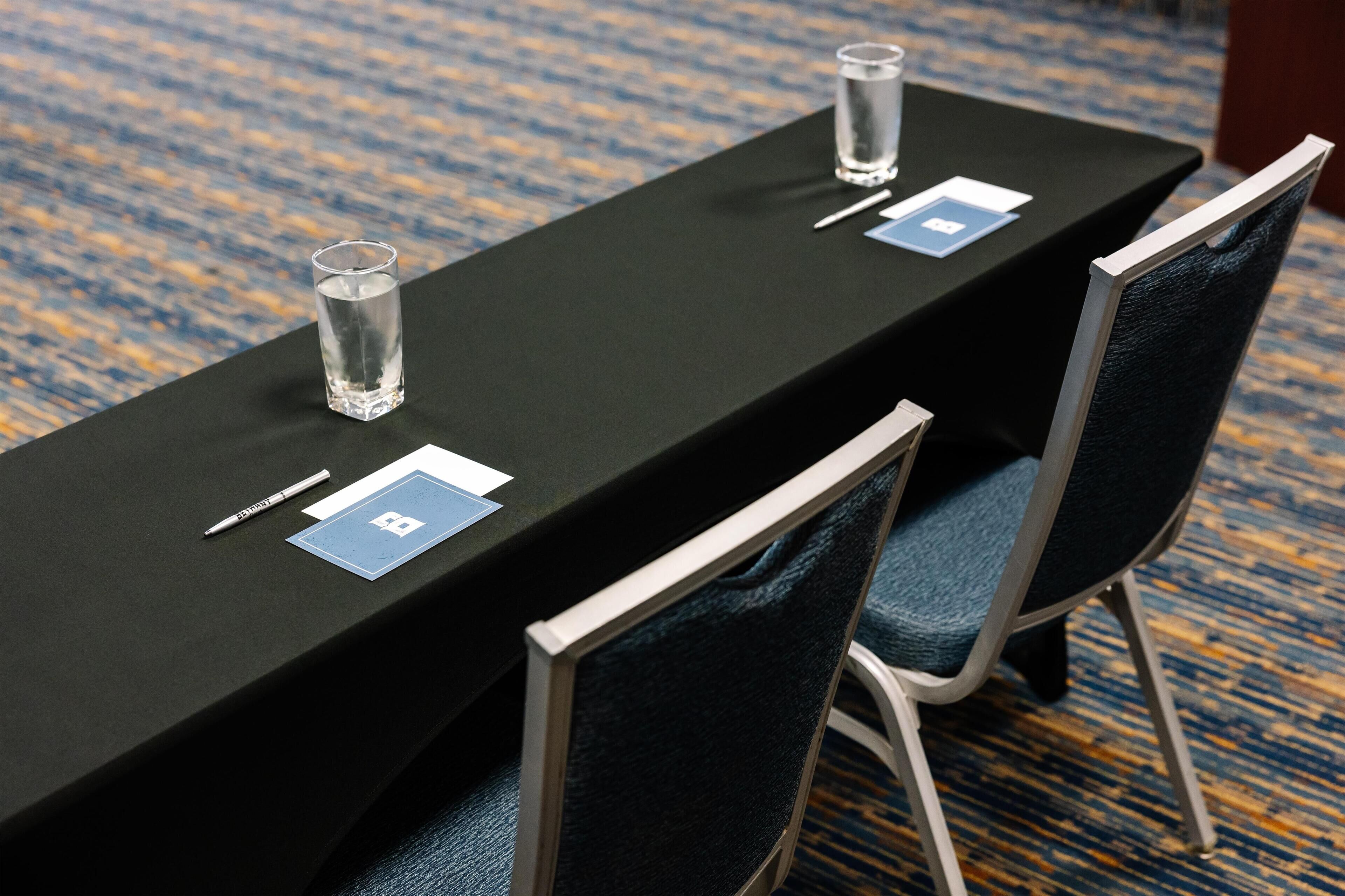 A conference table with name cards, pens, and glasses.