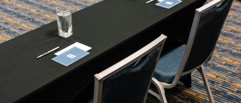 Een vergadertafel met naamkaartjes, pennen en glazen.