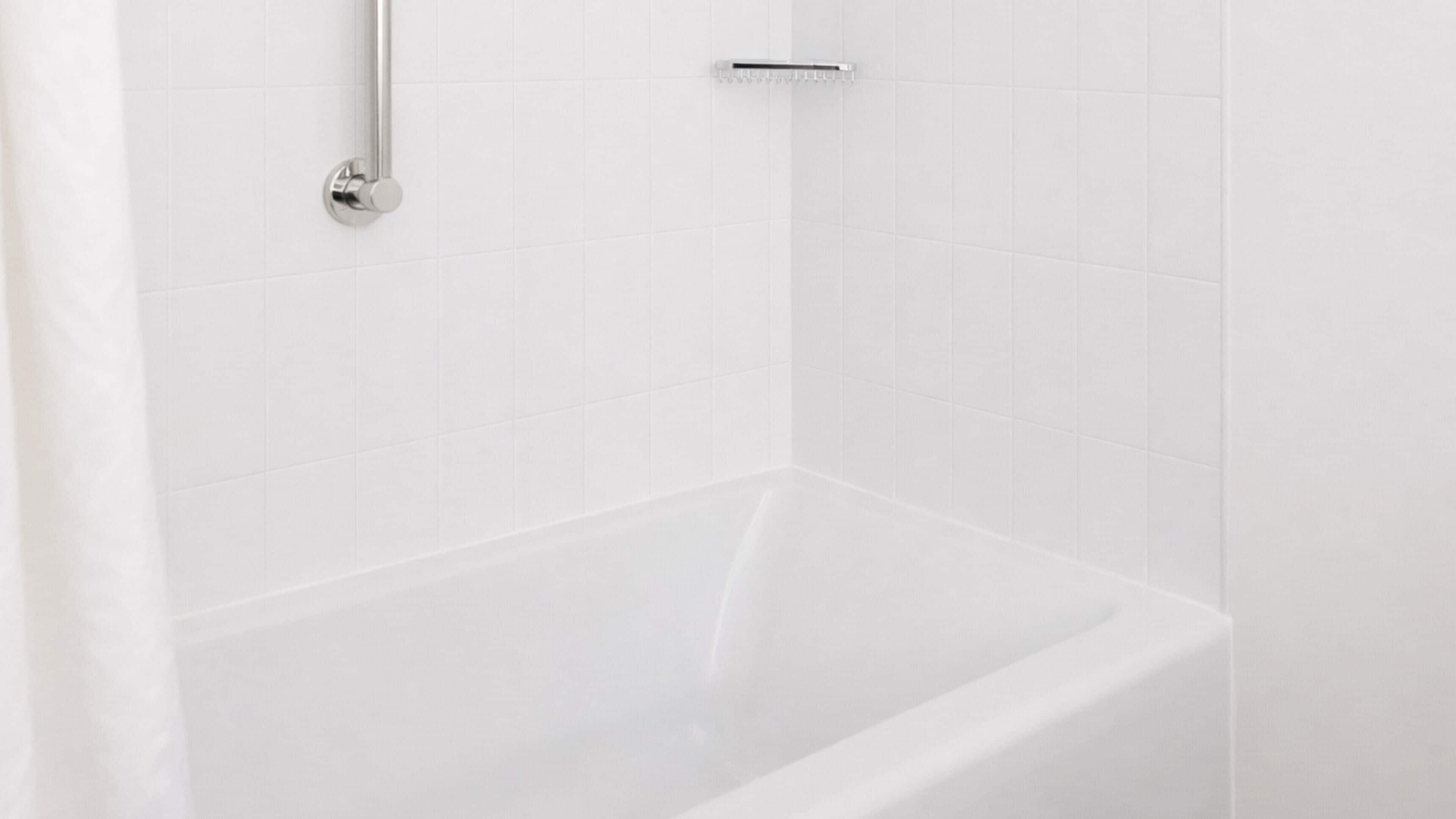 Eine weiße Badewanne mit einem Chromarmaturenset und einer Duschbrause.