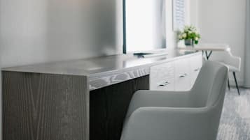 A modern office desk with a dark wood finish and a white chair.