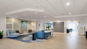 A spacious living area with a blue sofa, a small side table, and a decorative wall piece. - Hotel Bethany Beach (Bethany Beach)