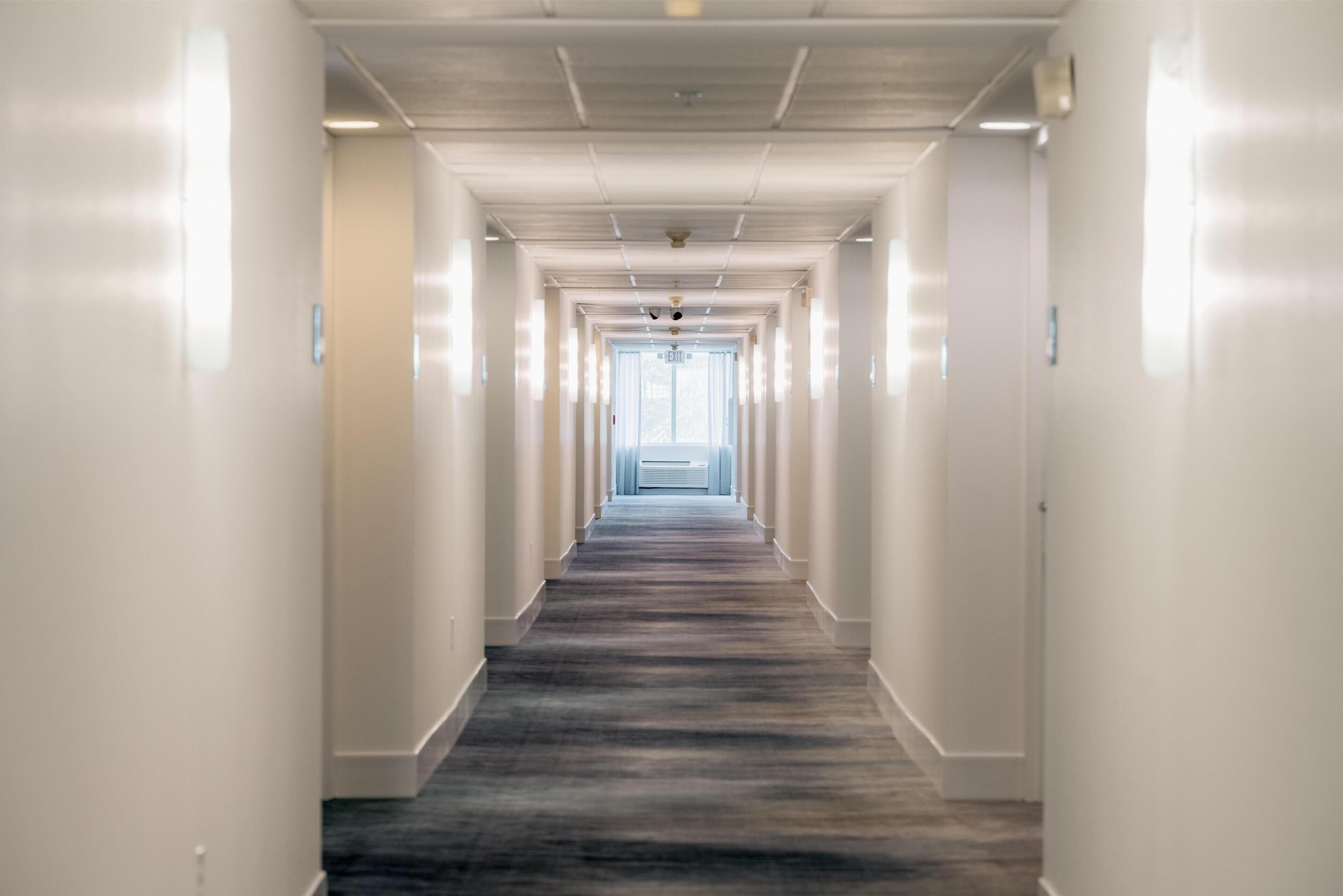 A long, narrow hallway with white walls and a patterned carpet.