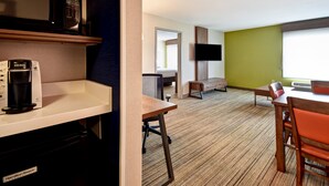 Une chambre d’hôtel équipée d’une kitchenette, d’un téléviseur fixé au mur, d’une table à manger en bois avec des chaises et d’une grande fenêtre.