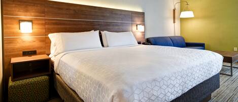 A hotel room with a large bed, two bedside tables, a nightstand, a chair, and a lamp.