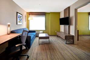 A modern hotel room with a sofa, desk, and TV. - Holiday Inn Express Newport North - Middletown by IHG (Middletown)