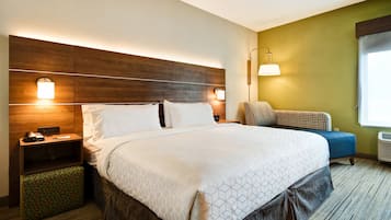 Una habitación de hotel con una cama grande, mesitas de noche, un escritorio y una silla.