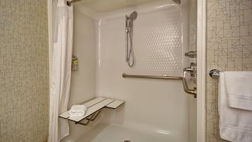 A walk-in shower with a glass door, a towel rack, and a small shelf.