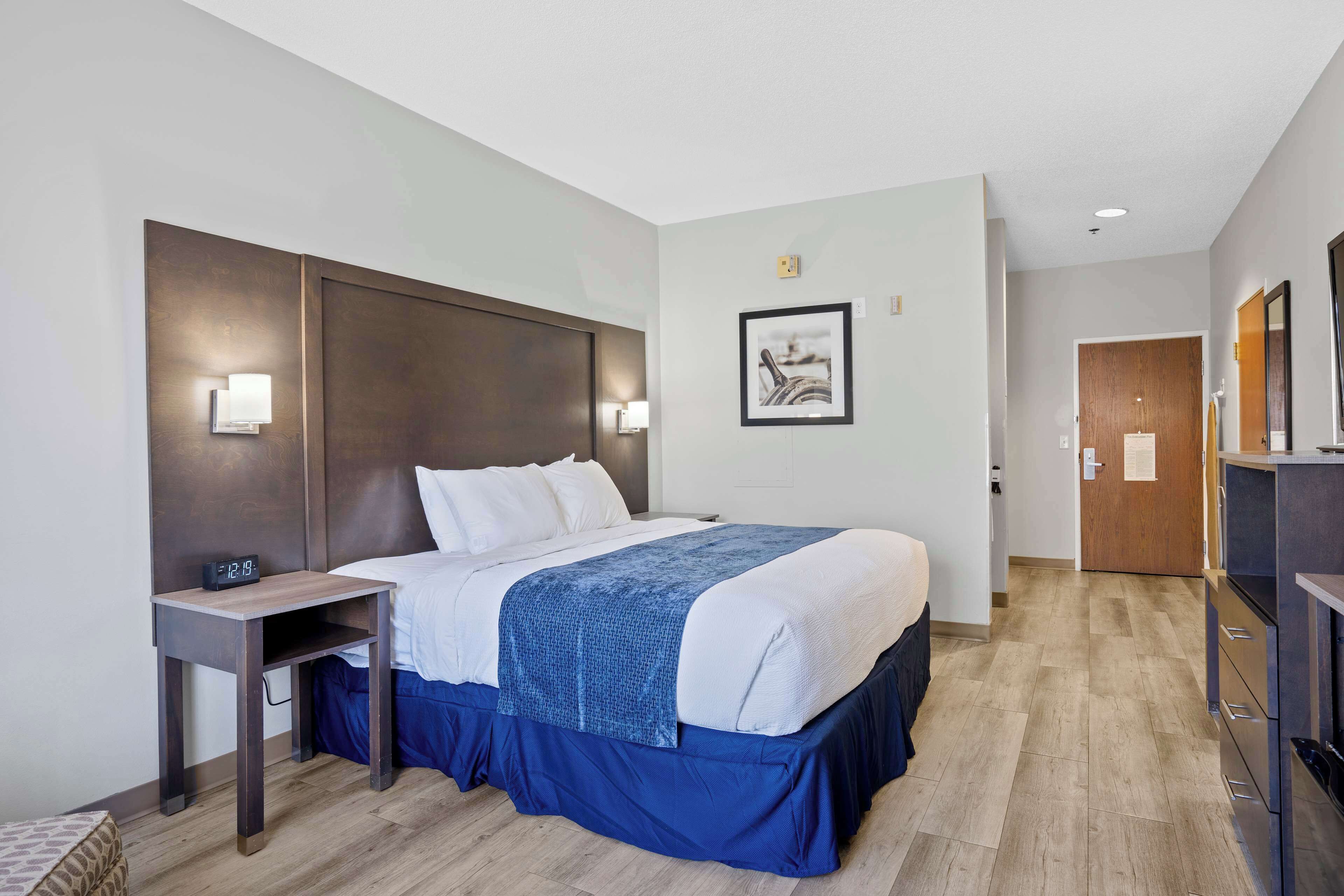 A hotel room with a large bed, bedside tables, a desk, and a wardrobe.