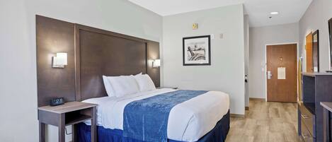 A hotel room with a large bed, bedside tables, a desk, and a wardrobe.