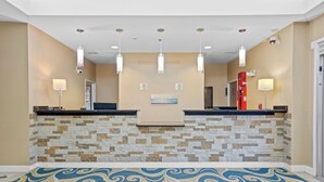 A reception area with a stone wall, a reception desk, and a blue patterned floor. - Blue Water Inn & Suites, BW Signature Collection (Sneads Ferry)