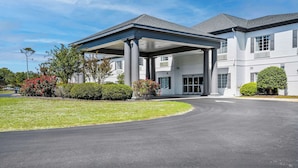 A modern building with a covered entrance, a well-maintained lawn, and a clear sky. - Blue Water Inn & Suites, BW Signature Collection (Sneads Ferry)