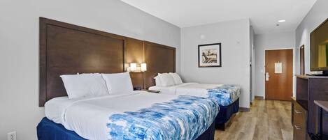 Camera d'albergo con due letti, una testiera in legno, un quadro appeso e un pavimento in legno.