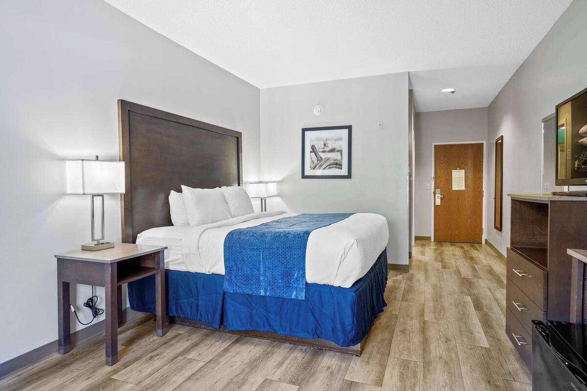 Een hotelkamer met een bed, nachtkastjes, een bureau en een kledingkast.