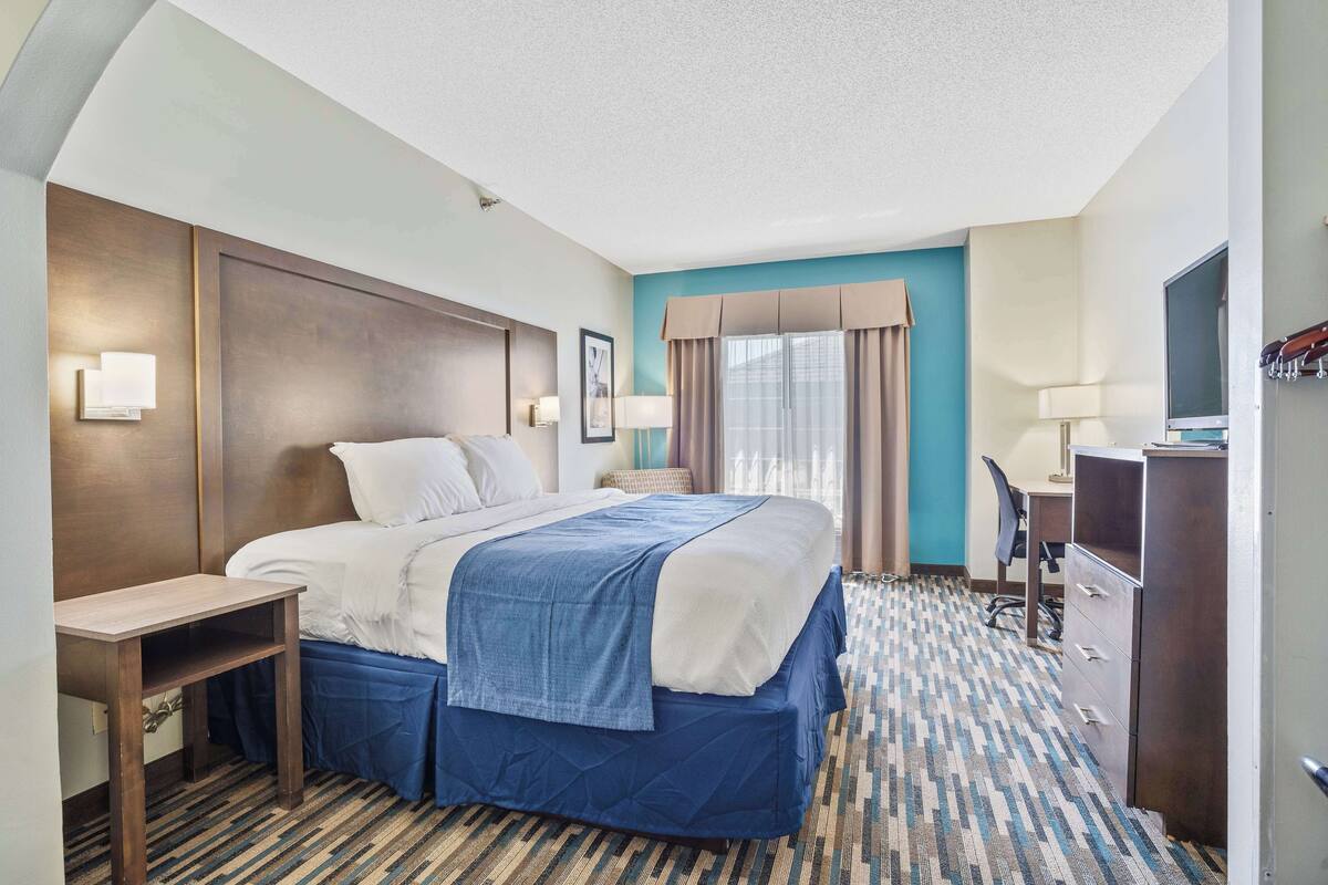 Een hotelkamer met een bed, nachtkastje, bureau, stoel en televisie.