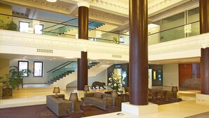 A spacious lobby with a grand staircase, multiple seating areas, and a large chandelier. - The Dostyk Hotel (Almaty)