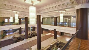 A grand lobby with a high ceiling, large chandeliers, and a spacious seating area with sofas and tables. - The Dostyk Hotel (Almaty)