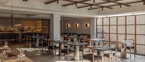 A spacious restaurant with high ceilings, exposed beams, and a mix of wooden and metal furniture.
