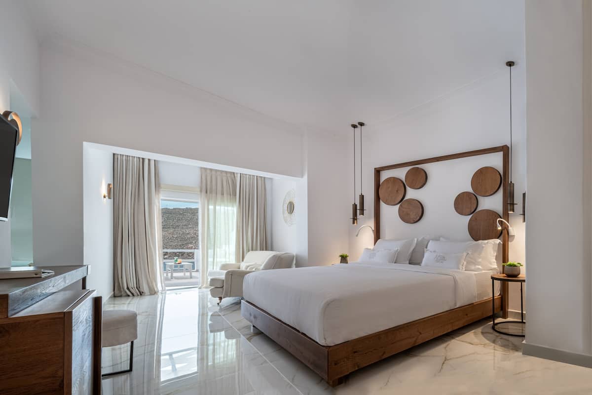 Ein modernes Schlafzimmer mit einem Holzbett, einem Schreibtisch und einem Balkon mit Vorhängen.