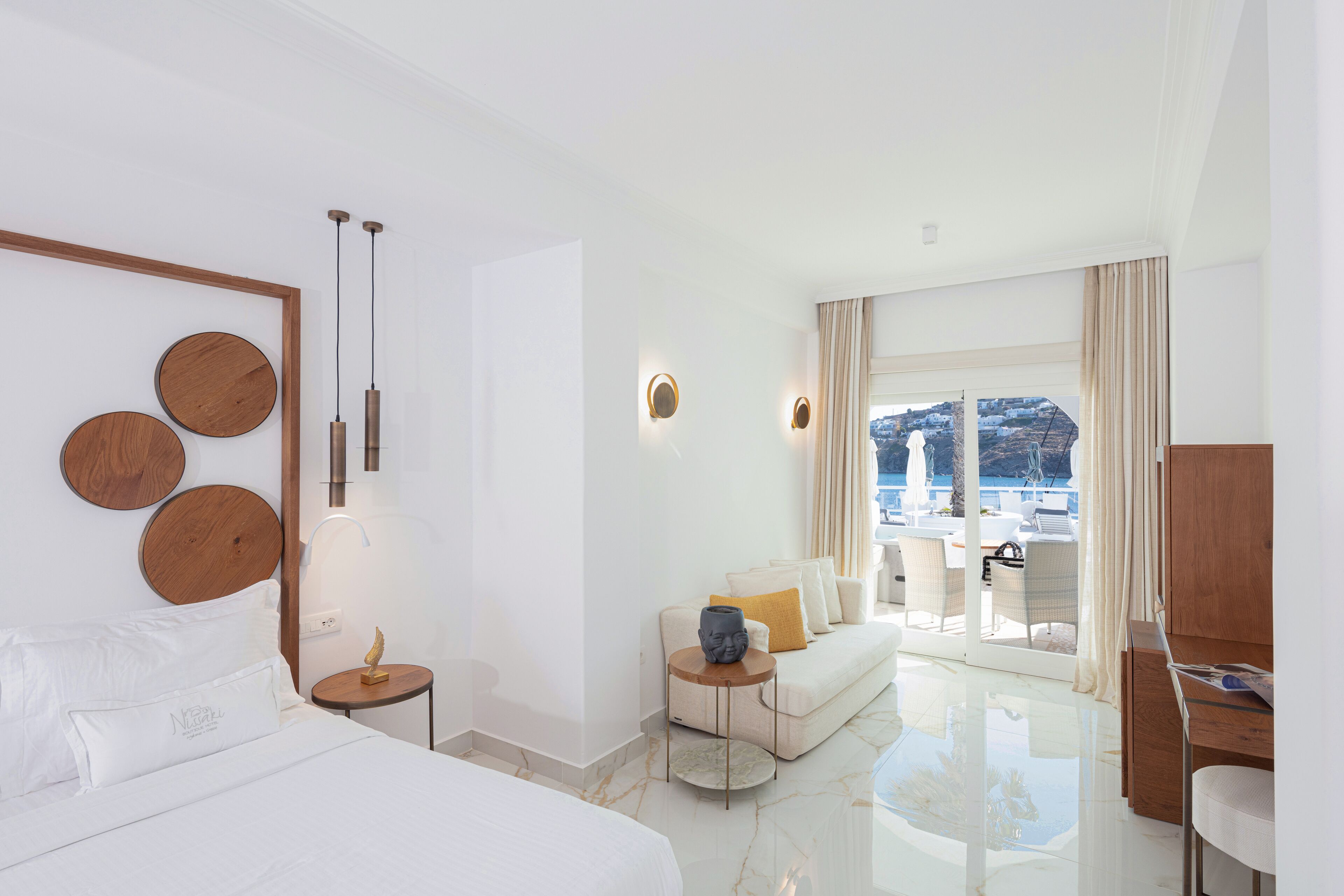 Ett modernt hotellrum med en stor säng, en soffa, en matplats och utsikt över havet.