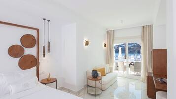 Ett modernt hotellrum med en stor säng, en soffa, en matplats och utsikt över havet.