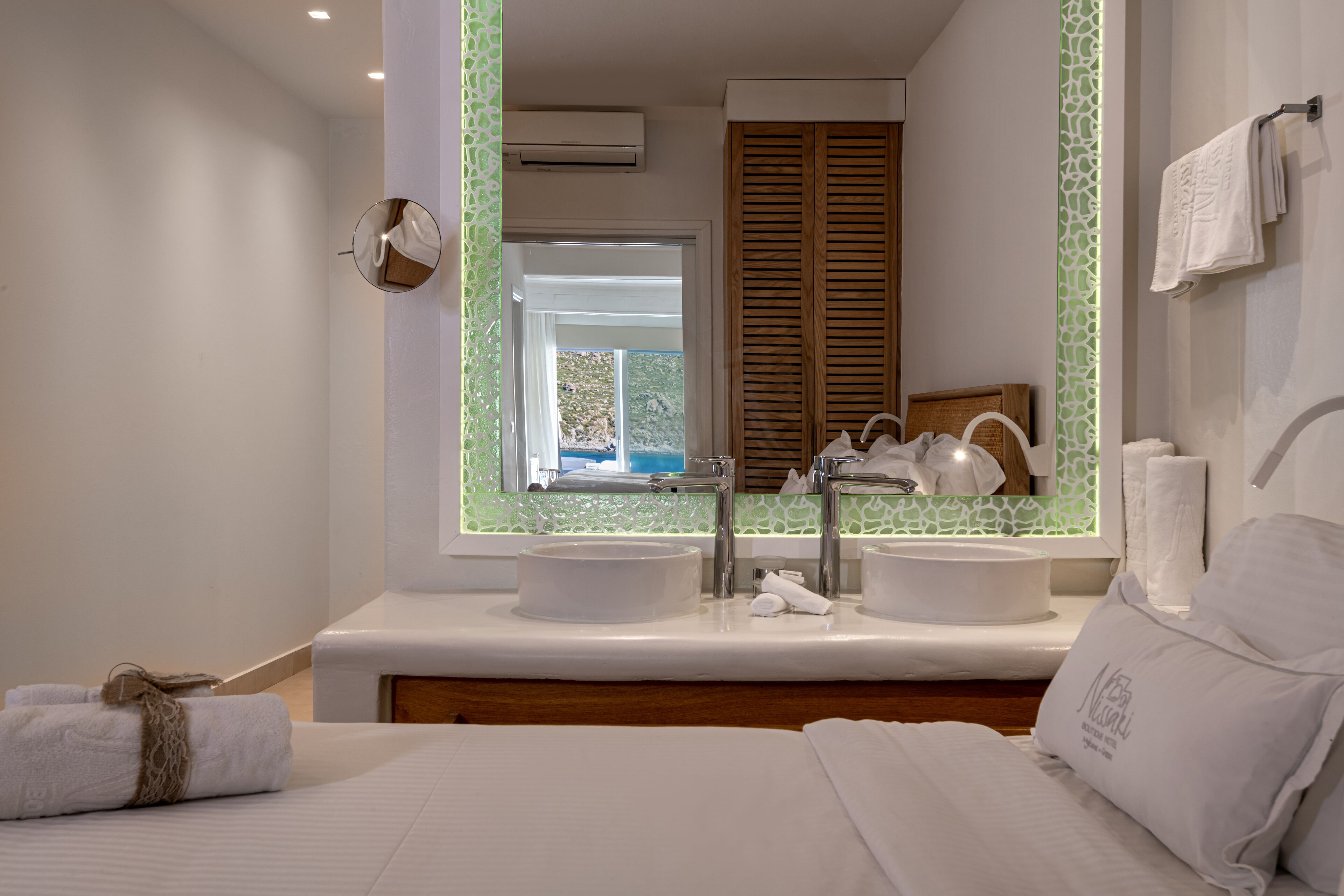 Un baño moderno con dos lavamanos, un espejo grande y vistas al exterior.