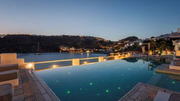 A swimming pool with a view of a hillside and a body of water in the background.
