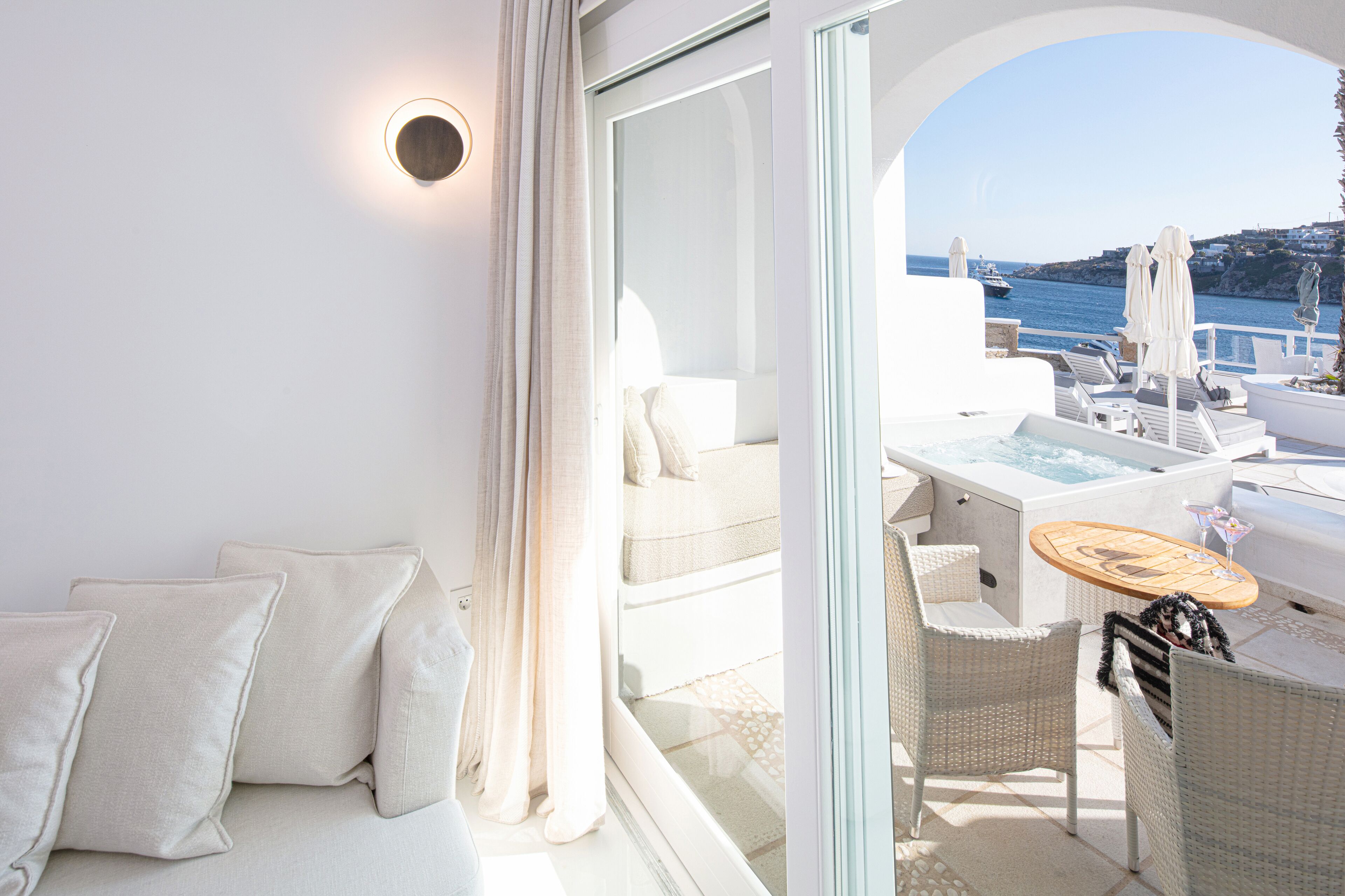 A modern outdoor seating area with a sofa, chairs, and a table, overlooking a scenic coastal view.