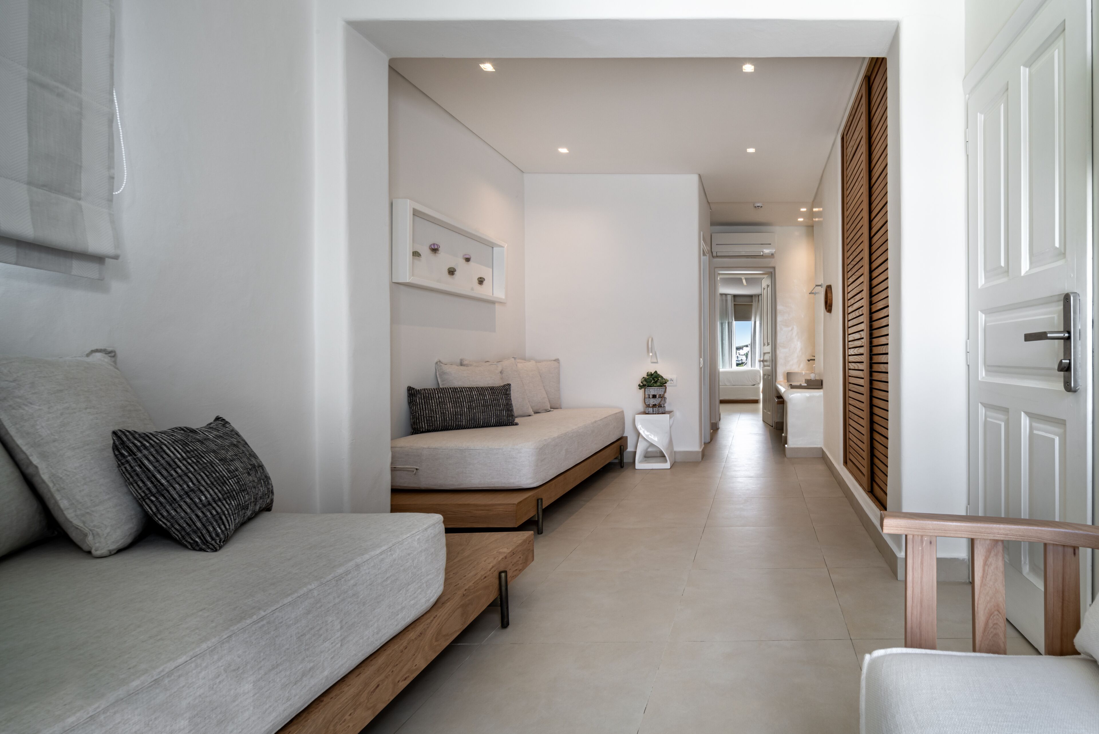 Un salon moderne et minimaliste, avec un canapé, une petite table d’appoint et un banc en bois.