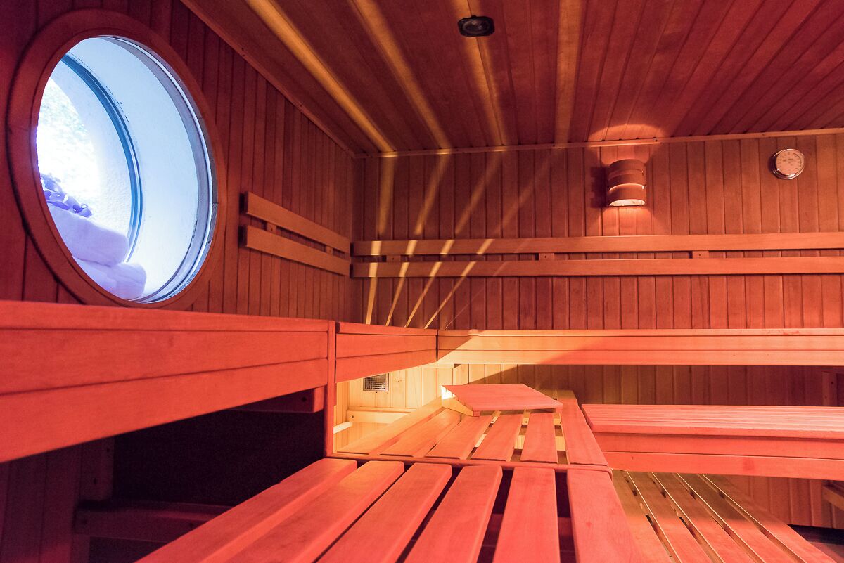 Una sauna con bancos de madera y un tragaluz circular.