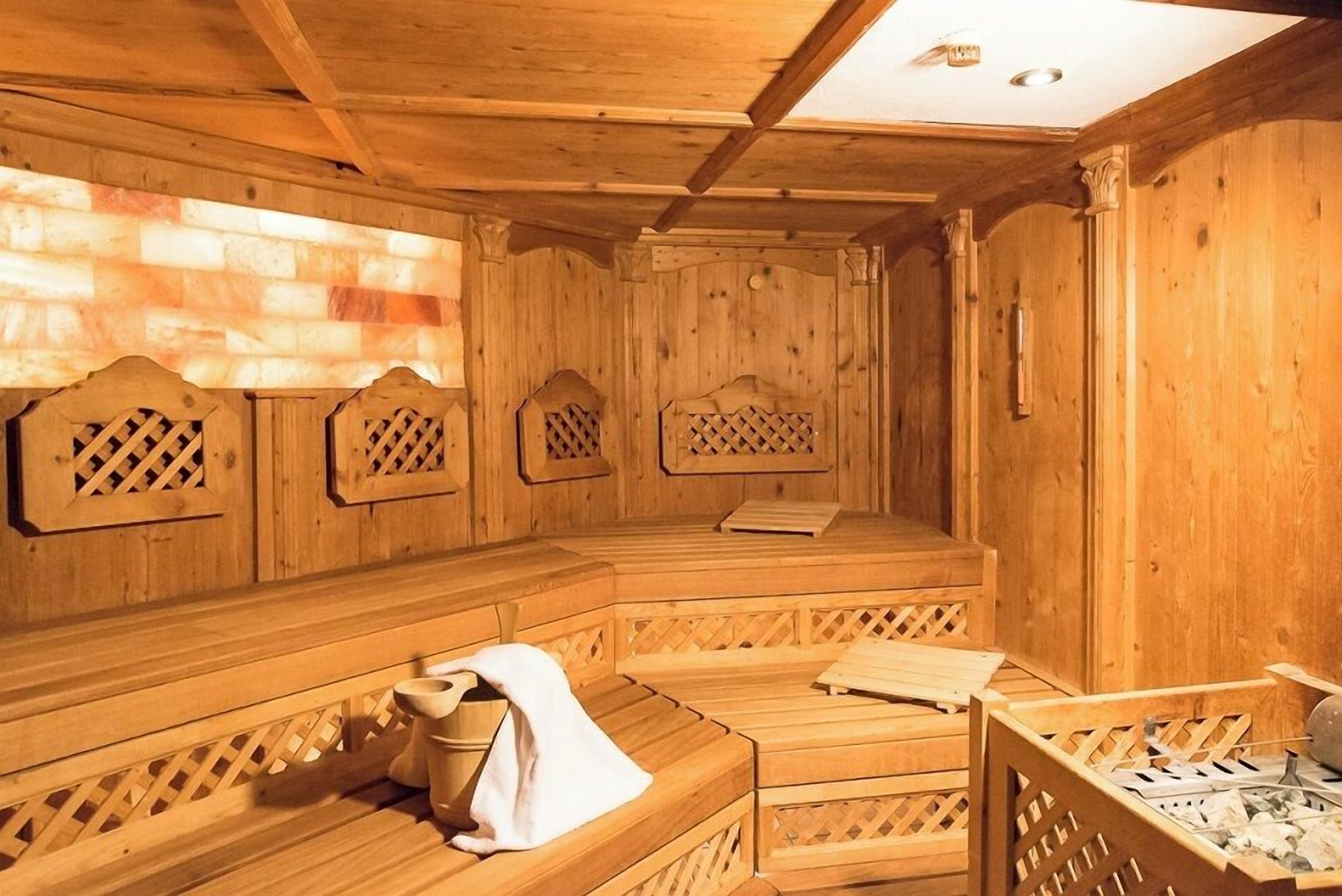 A wooden sauna with benches and a bench seat, featuring lattice designs and a sloped ceiling.