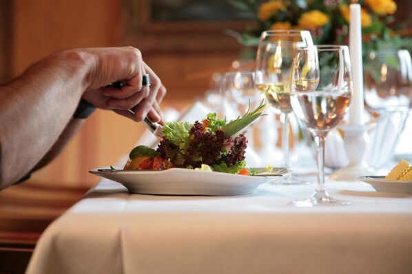 A dining table with a plate of salad and wine glasses.