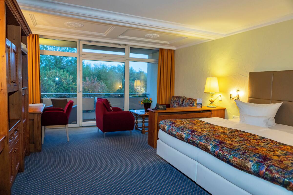 Ein Hotelzimmer mit Bett, Schreibtisch, Stuhl und Blick ins Freie.