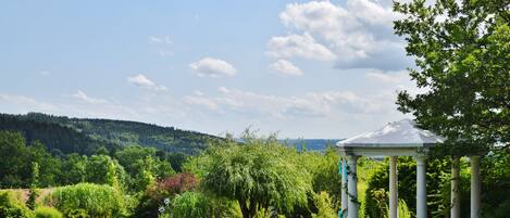 A gazebo in a lush garden with a clear sky.