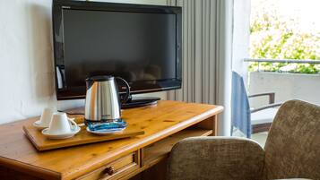 A hotel room with a wooden desk, a television, a coffee maker, and a chair.