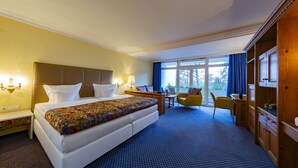 A hotel room with a large bed, bedside tables, a desk, a chair, and a wardrobe. - Hotel Reiterhof Bellevue Spa & Resort (Wirsberg)